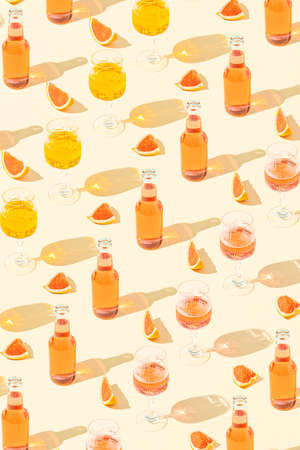 Summer creative cocktails pattern with bottles, glasses, slices of fresh grapefruit against a pastel beige background. Minimal vacation party concept.の写真素材