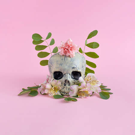 Skull with colorful flowers on pink background. Atmosphere witch ritual. Halloween creative fashion love concept.の写真素材