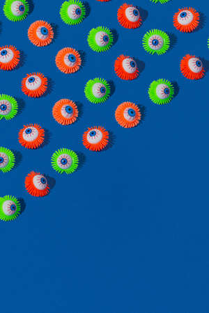 Halloween pattern made with colorful eyeball toy on vivid blue background. Creative spooky concept.の写真素材