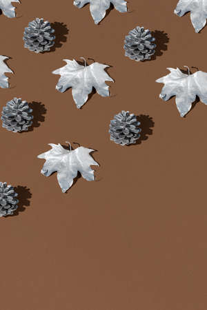 Autumn pattern with dry leaves and cones on a brown background. Creative holiday concept. Flat lay.