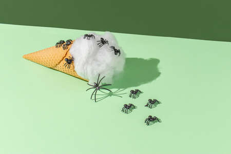 Ice cream cone with spider web and spiders. Spooky Halloween concept. Vivid green colors background.の写真素材