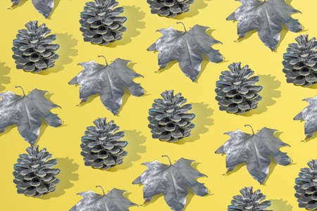 Autumn pattern with dry leaves and cones on a yellow background. Creative holiday concept. Flat lay.の写真素材