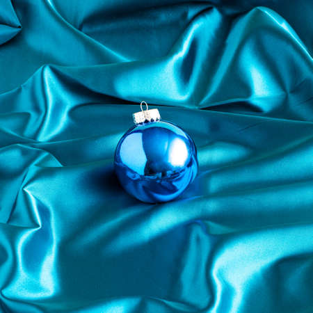 Blue shiny Christmas tree balls on luxurious blue satin. Elegant decorative holiday background. Creative Xmas or New year festive holiday concept.の写真素材