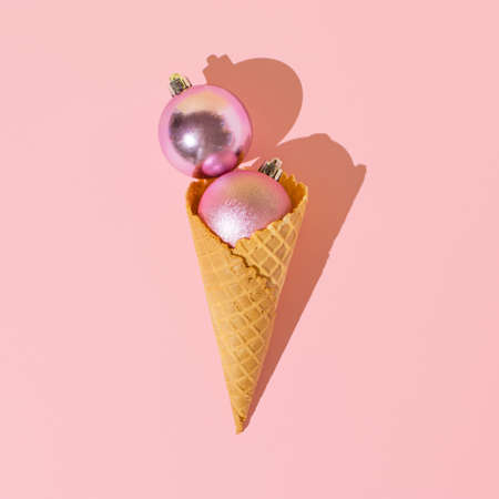 Ice cream cone with shiny pink Christmas baubles. Minimal xmas candy concept.の写真素材