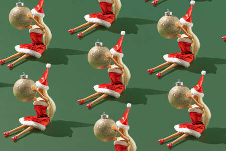 Creative Christmas pattern with a female Santa Claus
holds a decorative bauble against a green background. Minimal Xmas or New Year celebration concept.の写真素材