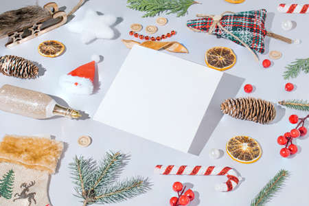 Creative Christmas composition with holiday decorations and white paper card on a gray background. Trendy New year template.の写真素材