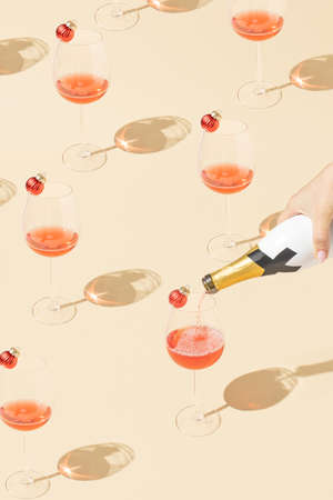 Creative pattern made with wine glass and bottle and Christmas baubles. Minimal beige New Year party background.の写真素材