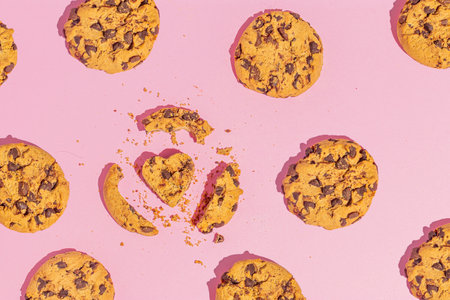 Composition with chocolate cookies and heart shaped cookies against a light pink background. Love or food concept. Flat lay.の写真素材