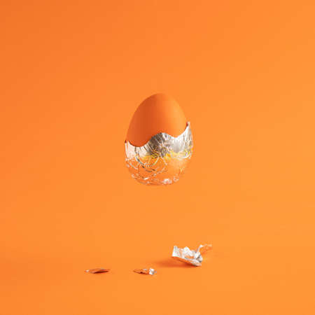 Creative Easter egg with foil against an orange background. Creative holiday or futuristic concept.