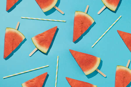 Trendy pattern with fresh watermelon ice cream and colorful straws on a light blue background....