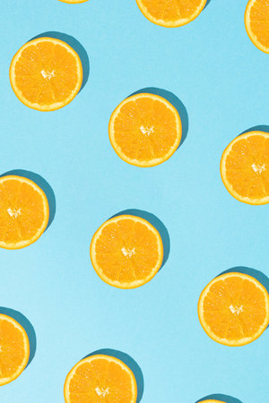 Creative summer pattern with sliced fresh orange on sunny blue background. Flat lay.の写真素材