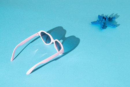 Trendy sunny scene with sunglasses and starfish on a blue background. Summer travel concept. Minimal beach idea.の写真素材