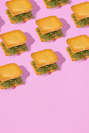 Christmas party creative pattern with fir branches between toast bread slices on pastel pink...