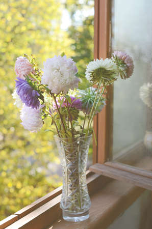 Autumn golden-daisy bunch in crystal vase on old wooden window-sillの写真素材