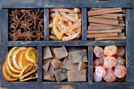 Dark chocolate, kumquats, dried orange slices, cinnamon, candied peels and star anise in old wooden crateの写真素材