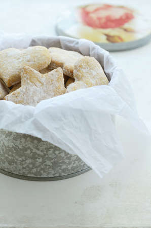 Star and heart shaped ginger cookies with sugar powder wrapped in parchment paper and placed in tin...