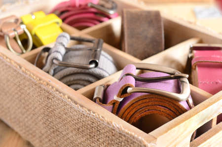 Set of casual leather belts in wooden organizer box on wooden background の写真素材
