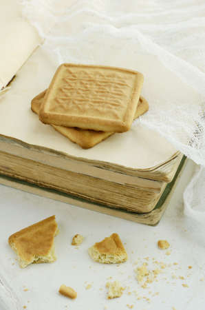 Two biscuits on vintage book pile on light backgroundの写真素材