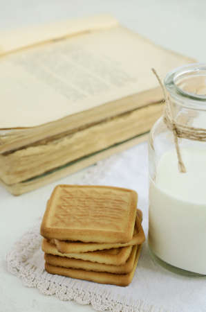 Short pastry and milk bottle on vintage lace doily on light backgroundの写真素材