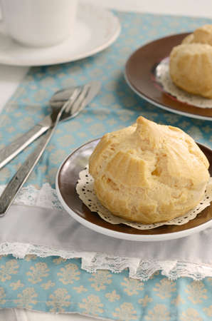 Eclair or profiteroles on small plate on French doily