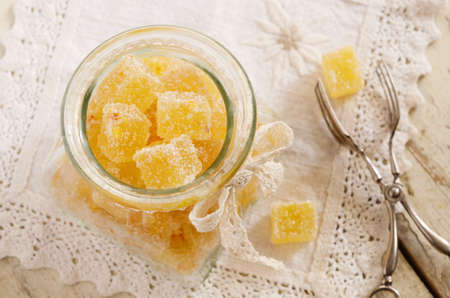 Homemade citrus jellies in sugar in glass jar decorated with lace ribbon and bowの写真素材