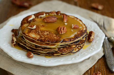 Homemade honey and pecan nuts pancakes on white plate and silverware for breakfastの写真素材