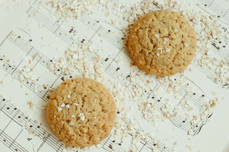 omemade oatmeal cookies on vintage music sheet topped with oatmeal flakesの写真素材