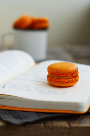 Orange colored  and passion fruit macaron over open diary with notesの写真素材