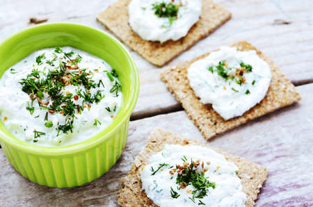 Homemade cottage cheese cream with spices and chopped dill and rye loaves sandwiches placed on...