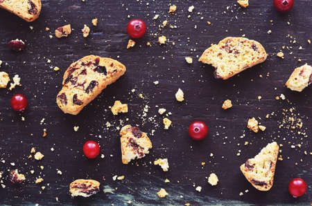 Crumbled biscotti and fresh winter cranberry on dark wooden backgroundの写真素材