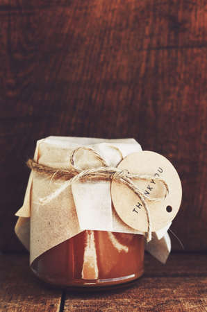 Homemade salted caramel sauce in glass jar with empty space on wooden backgroundの写真素材