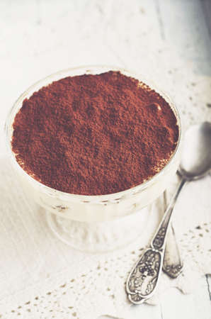 Homemade tiramisu dessert in a glass on white wooden backgroundの写真素材