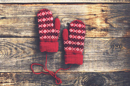 Pair of red woolen mittens on rustic wooden background