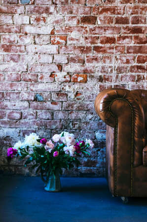 Loft interior details - leather sofa, bunch of flowers, brick wall and rough floorの写真素材