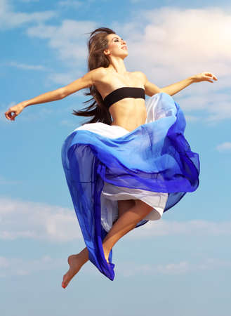 Beautiful jumping girl against a blue skyの写真素材