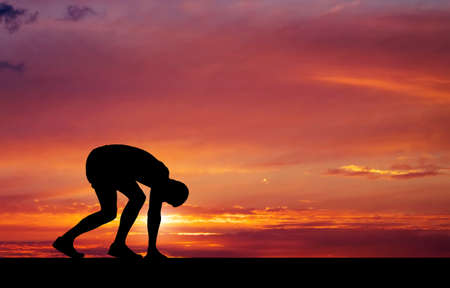 Silhouette of athlete in position to run on sunset background の写真素材