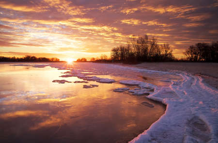Winter landscape with lake and sunset fiery sky. Composition of nature. の写真素材
