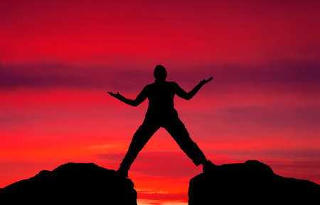 Silhouette of man on sunset fiery sky の写真素材