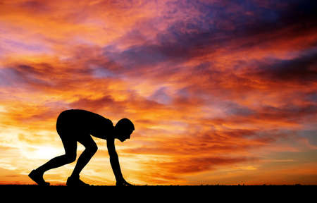 Silhouette of athlete in position to run on sunset の写真素材