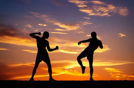 Silhouettes of two fighters on sunset fiery の写真素材