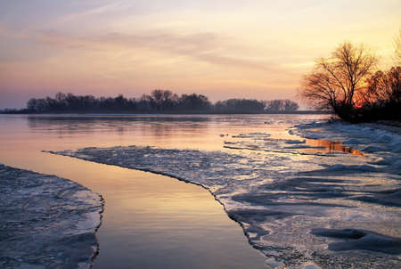 Winter landscape with lake and sunset sky. の写真素材
