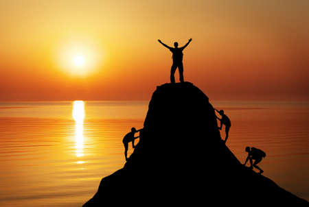 Silhouette of a mans on a mountain top on sunset background. Sport and active life conceptの写真素材