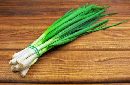 Bunch of fresh green onions laying on a wooden table. Fresh green onion on wooden backgroundの写真素材