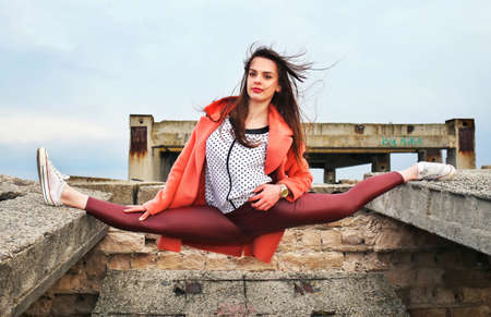 Beautiful sexy young girl gymnast took the pose of twine on an abandoned building. Fashion and...