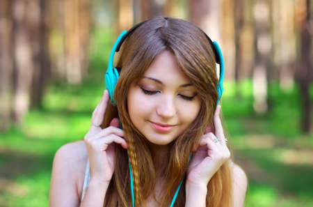 Beautiful girl listening to music with headphones at the parkの写真素材