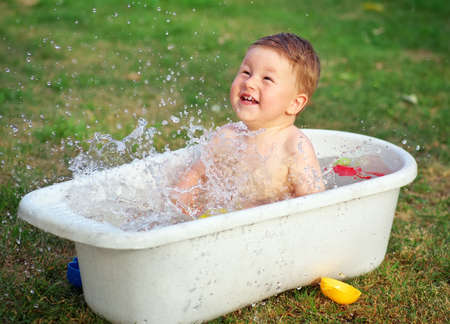 A small happy baby bathed in the bath and playing with toys.の写真素材