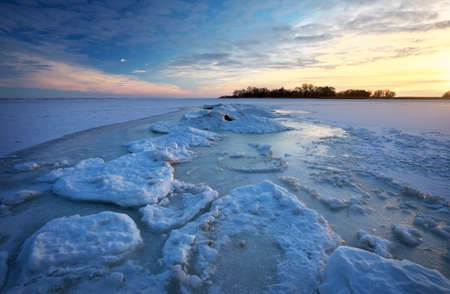 Winter landscape with frozen lake and sunset sky. Composition of nature.の写真素材