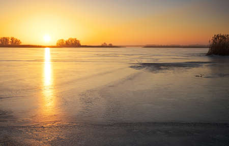 Winter landscape with frozen lake and sunset fiery sky. Composition of nature.の写真素材