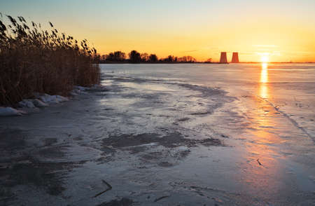 Beautiful winter landscape with sunset sky frozen reservoir and power plant.の写真素材