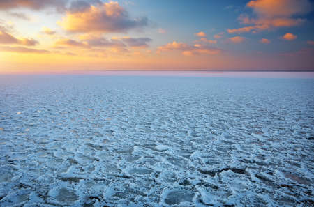 Winter landscape with frozen lake and sunset sky. Composition of nature.